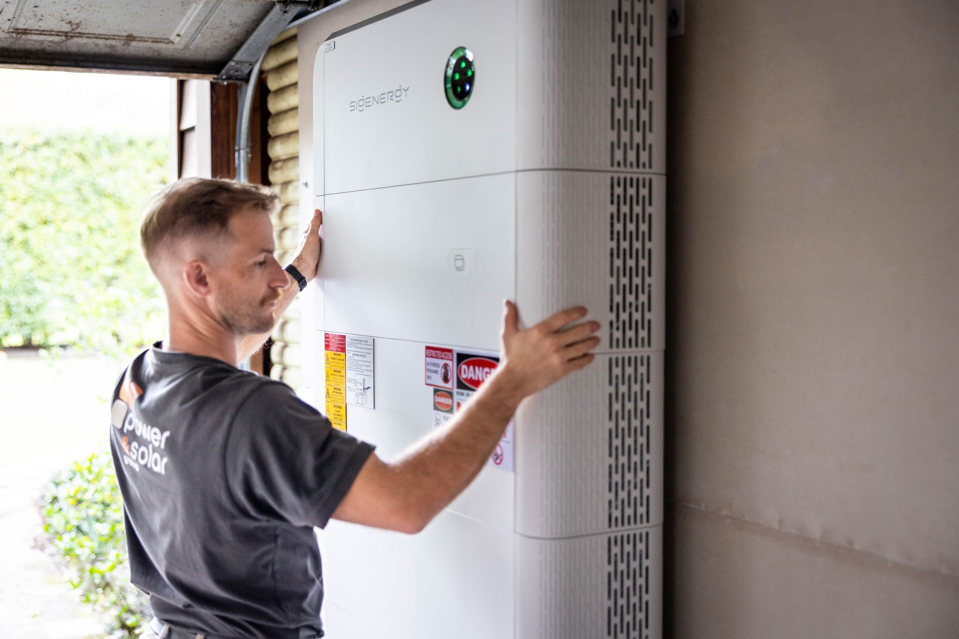 Technician installing a large white wall-mounted unit in a garage or utility room