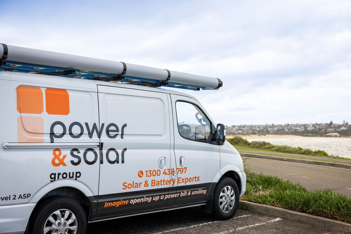 White Power & Solar service van by the water with solar panels on top and company branding on the side