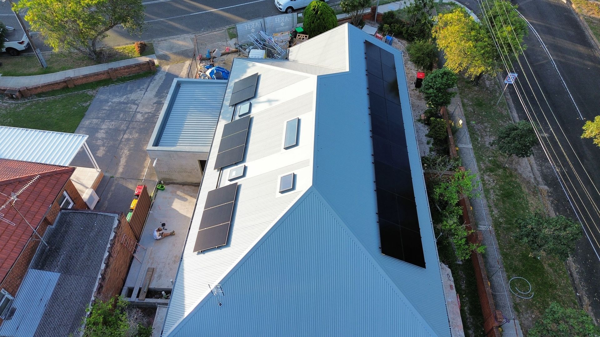 Aerial view of a modern white-roofed building beside a road and trees