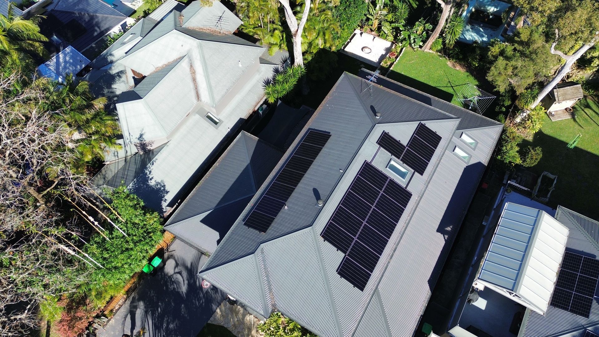 Worker in orange safety harness cleaning solar panels on a rooftop