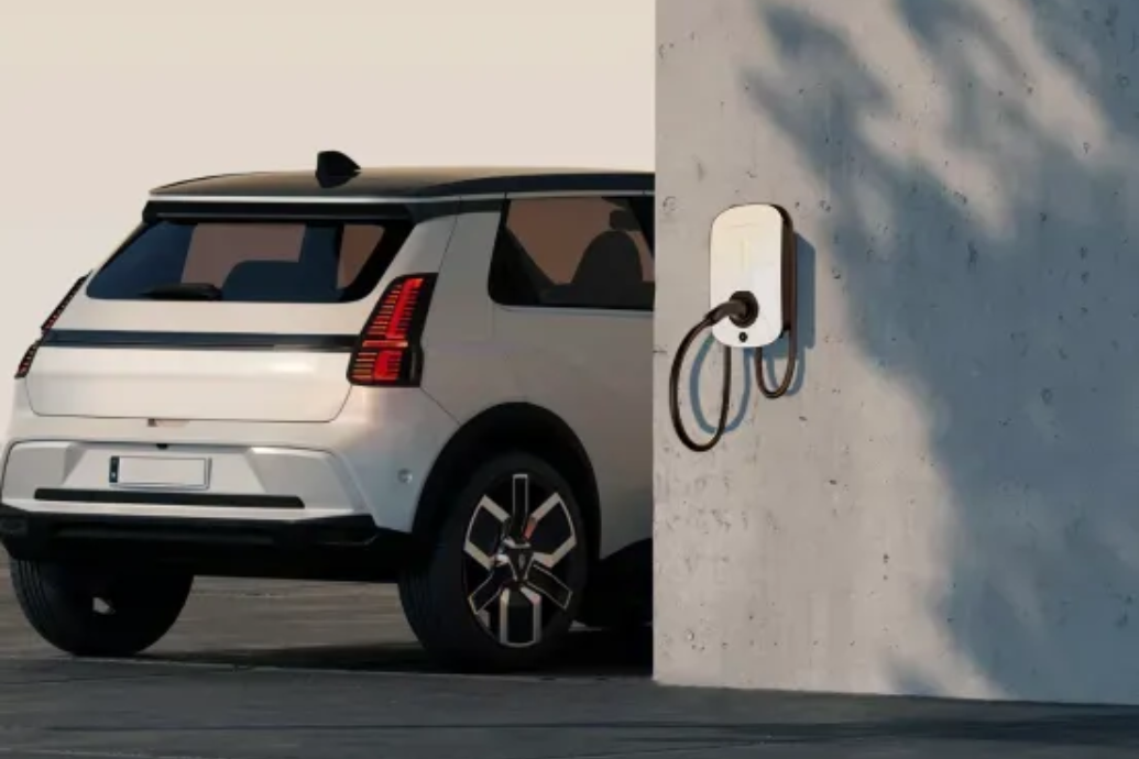 White electric SUV charging beside a wall-mounted charger in a parking area