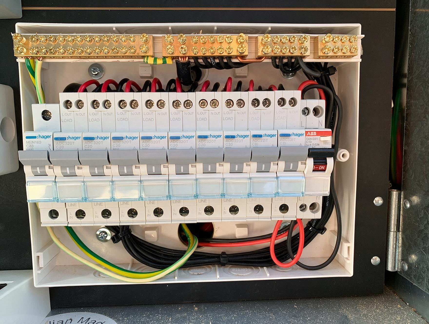 Electrical breaker panel with rows of white circuit breakers and colored wiring inside an open cabinet