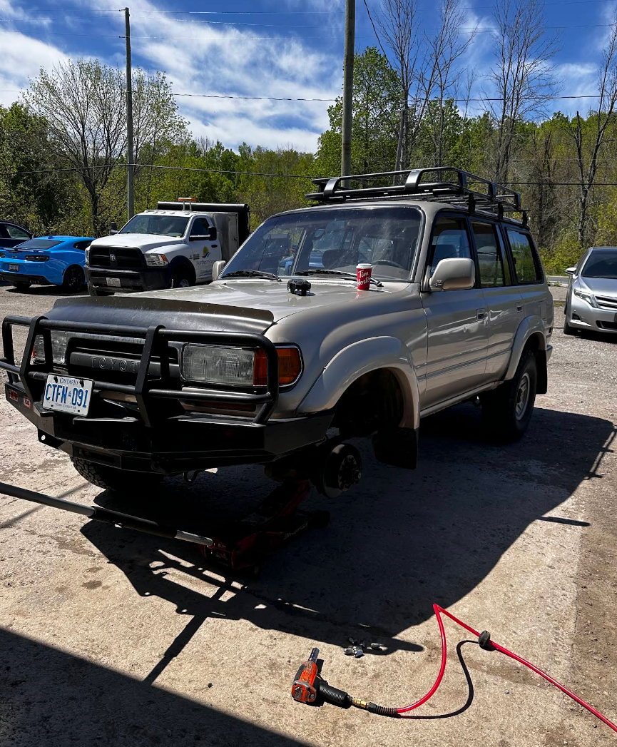 Silver SUV with a front bumper guard parked outdoors, with a red tow strap on the ground. | Fesserton Auto