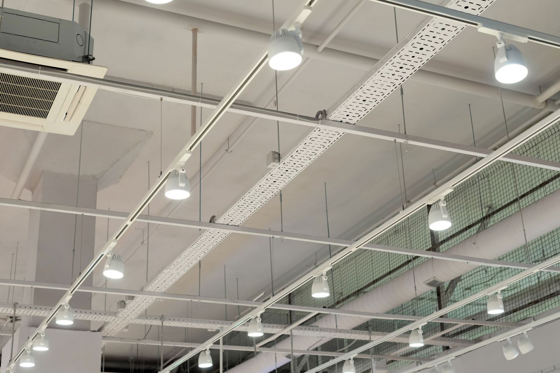White ceiling with overhead track lighting, ventilation ducts, and metal support beams.