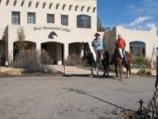 two people riding horses in front of bear mountain lodge