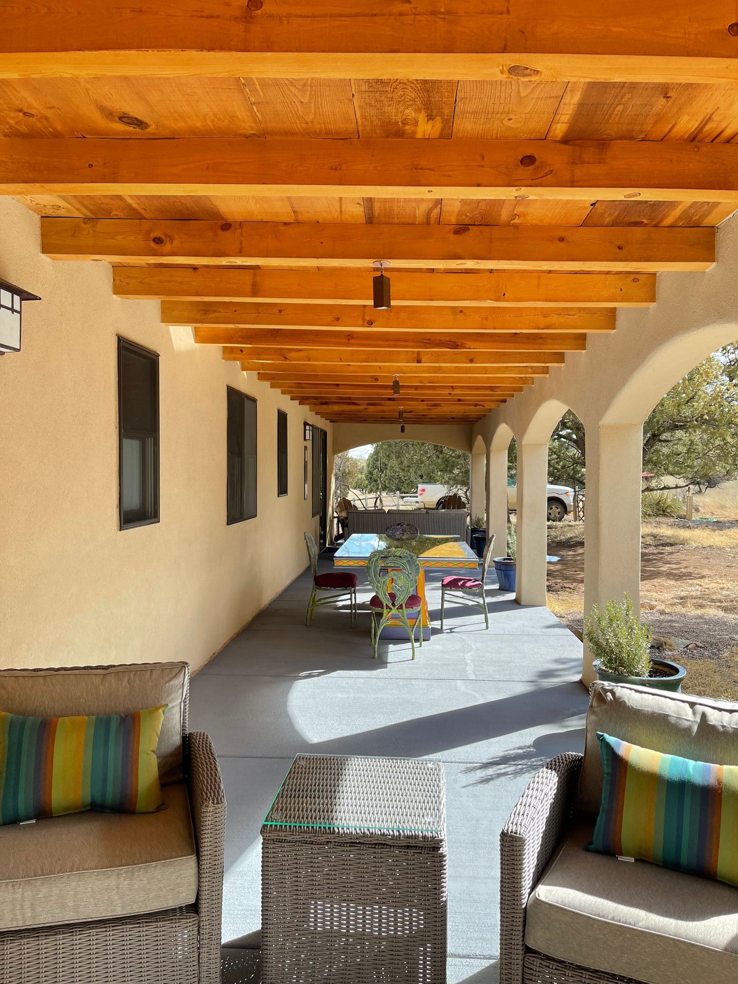 A porch with wicker furniture and a wooden ceiling