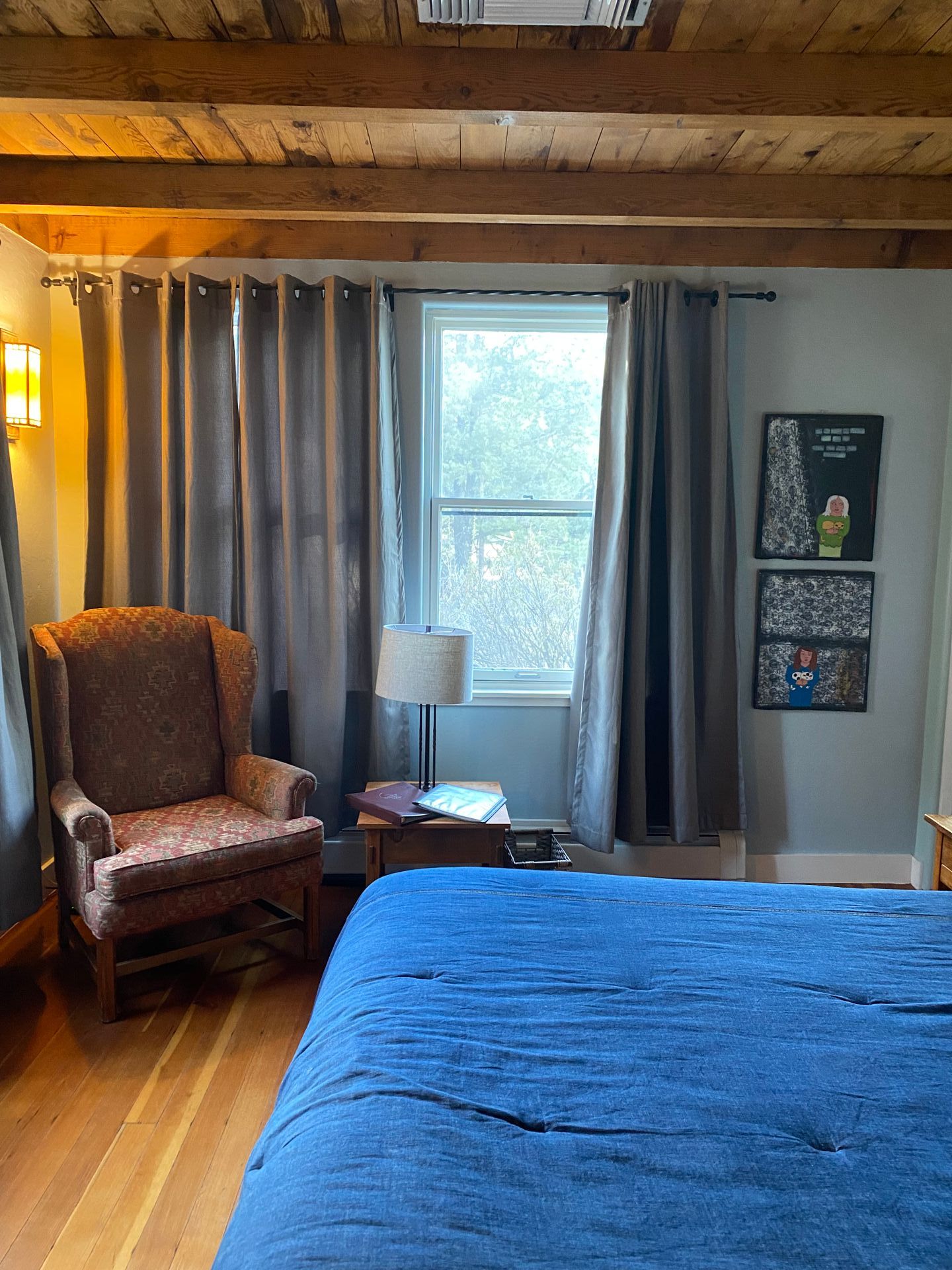 A bedroom with a bed , chair , lamp and window.