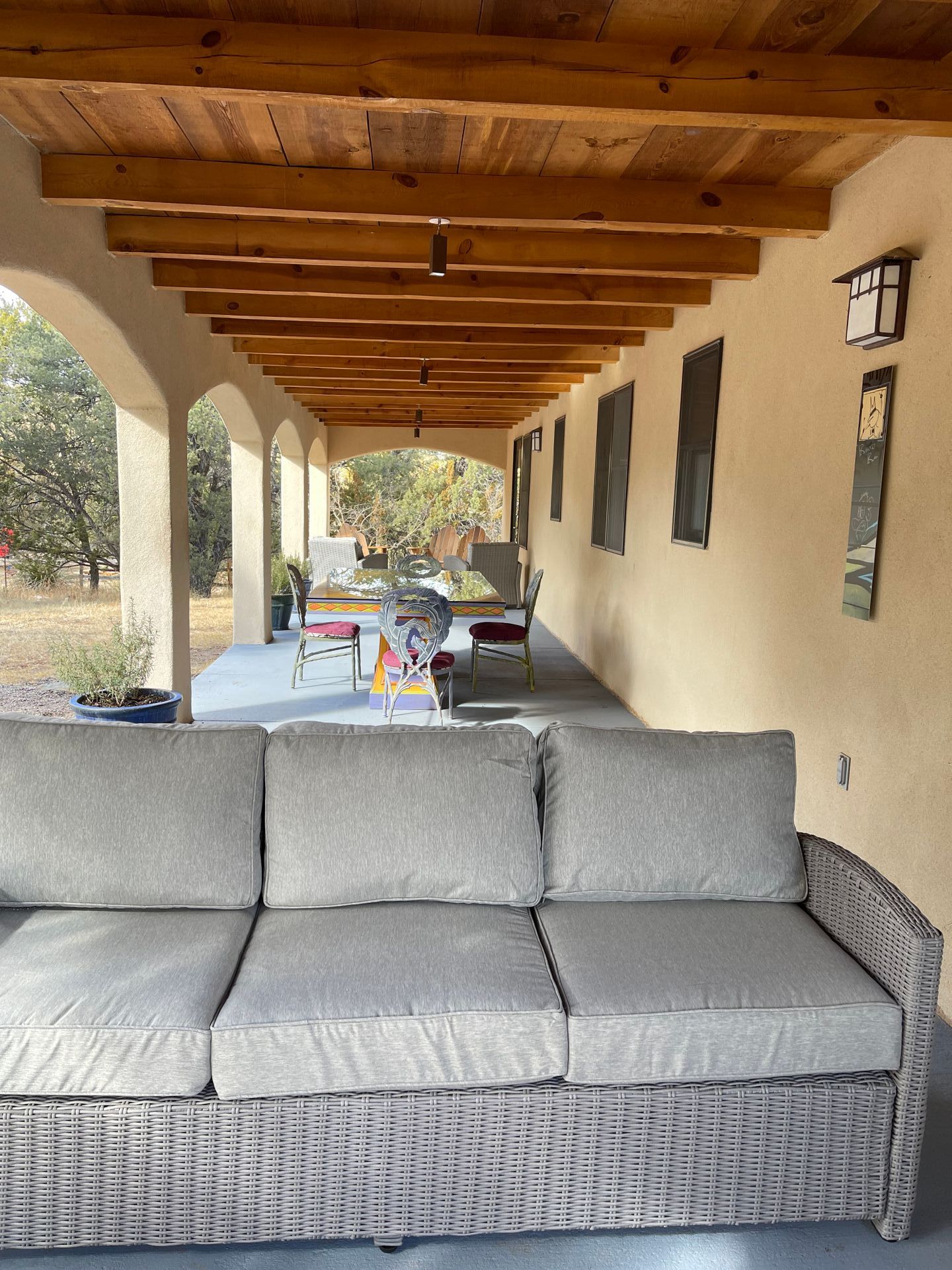 A couch is sitting on a porch under a wooden ceiling.