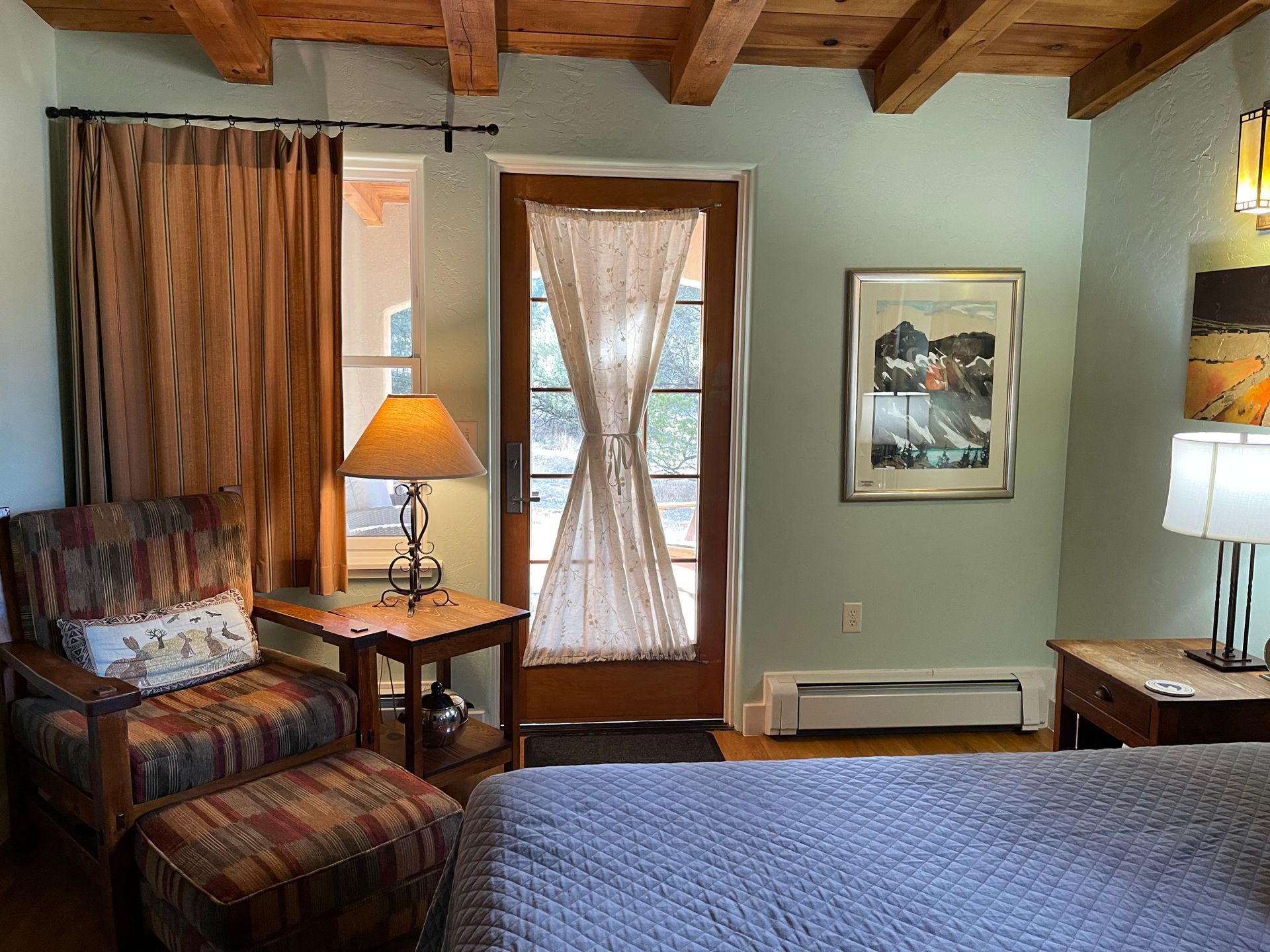A bedroom with a bed , chairs , lamps and a sliding glass door.