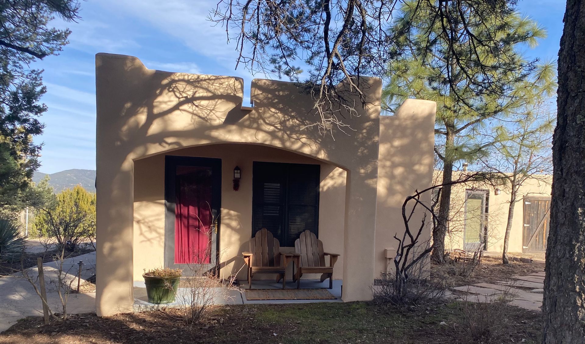 A small house with a red door is surrounded by trees