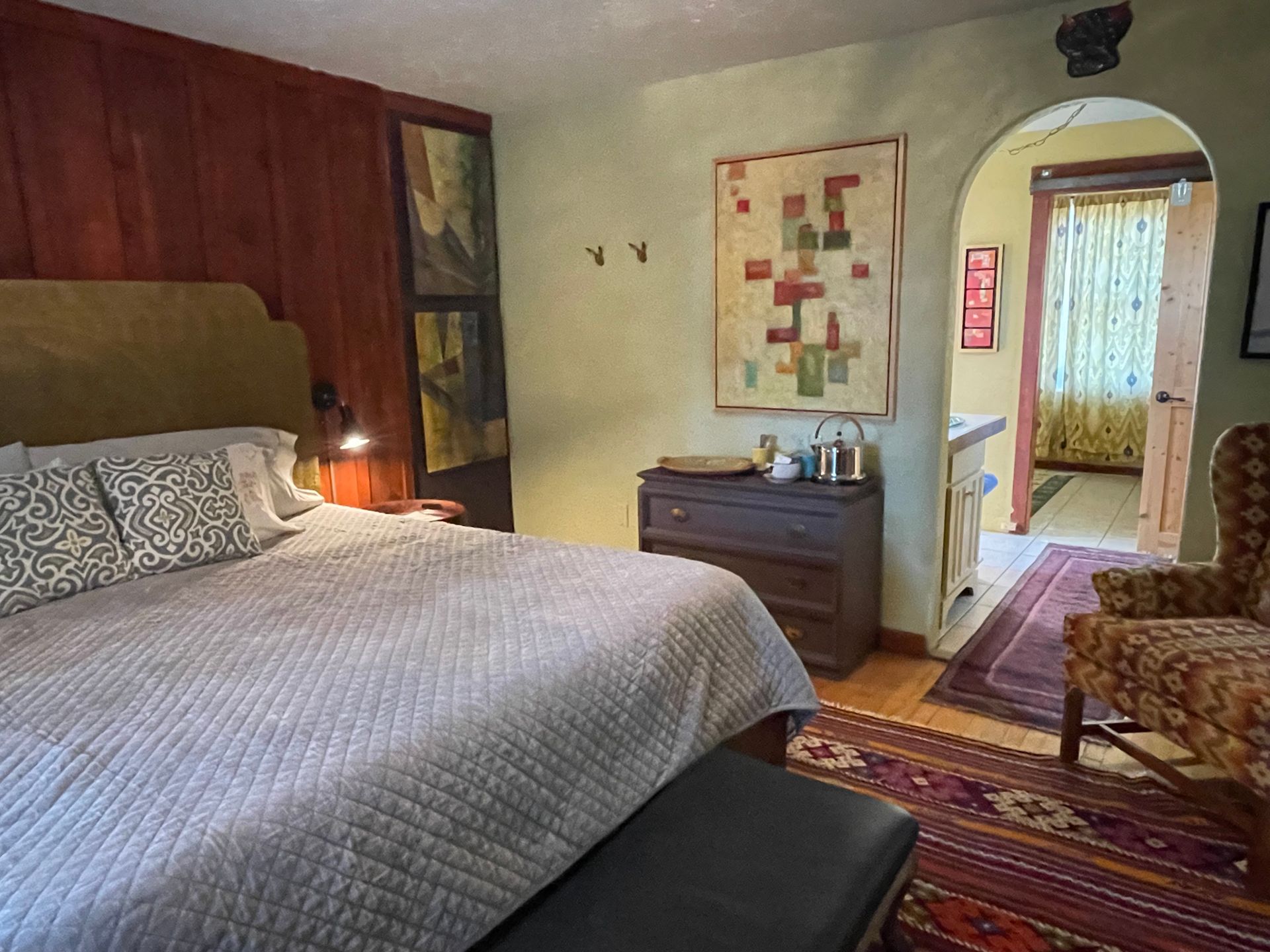 A bedroom with a bed , dresser , chair and rug.