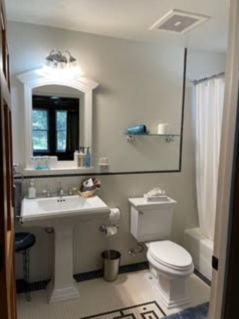 A bathroom with a toilet a sink and a mirror