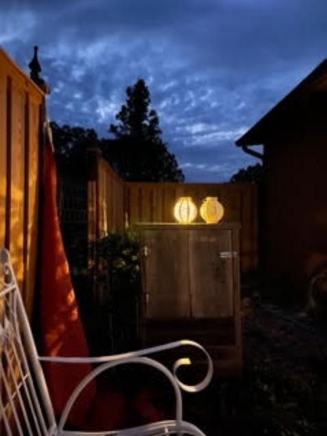 A white chair sits in front of a wooden fence at night