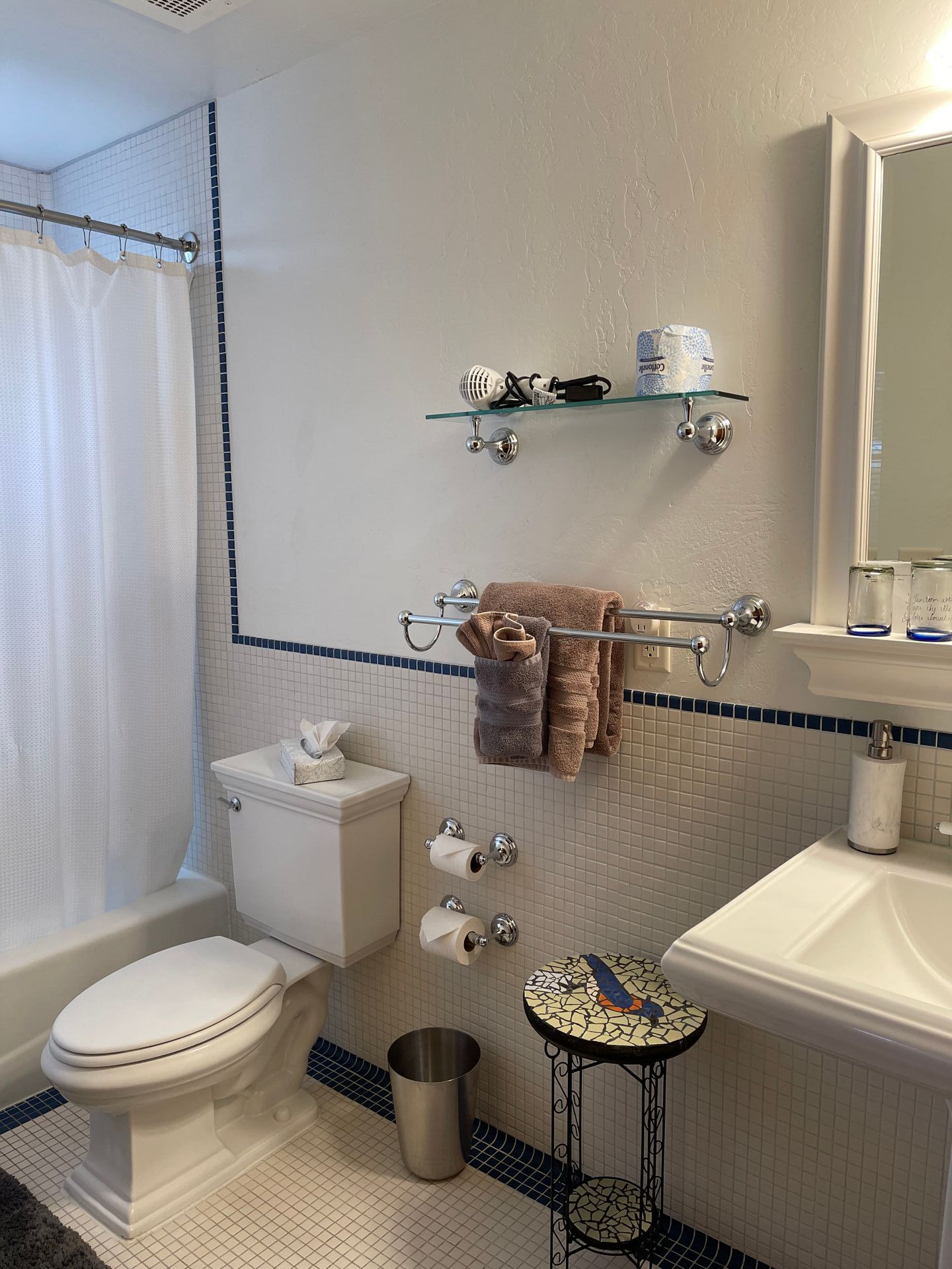 A bathroom with a toilet , sink , mirror and shower curtain