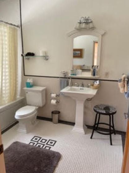 A bathroom with a toilet a sink and a mirror