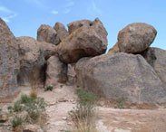 A large rock formation in the desert with a blue sky in the background.