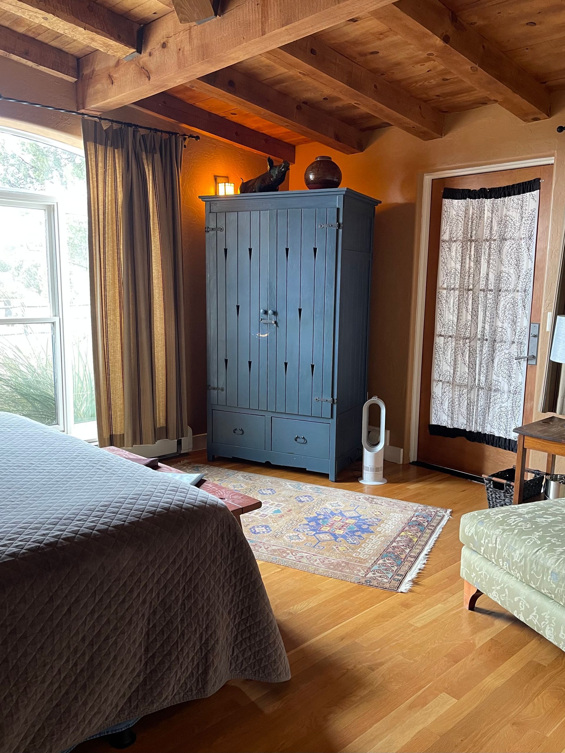A bedroom with a bed , wardrobe , chair and rug.