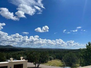 A view of a valley with trees and clouds in the sky