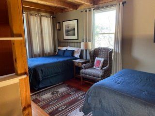 A bedroom with two beds , a chair and a window.