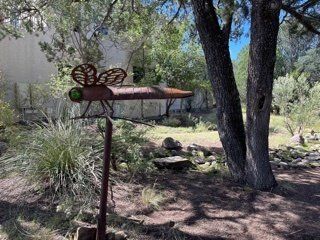 A metal sculpture of a dragonfly is sitting in the middle of a forest.