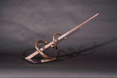 A statue of a snake holding a stick on a stand