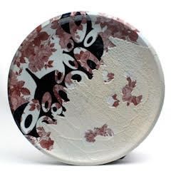 Decorative ceramic plate with floral and abstract patterns in red, black, and white.