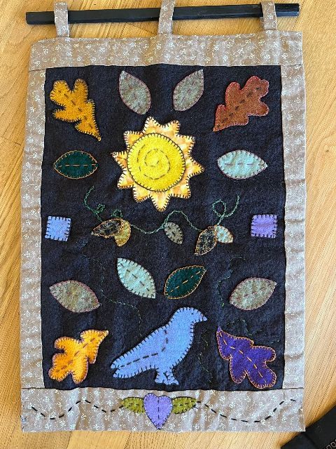 A quilt with leaves and a bird on it