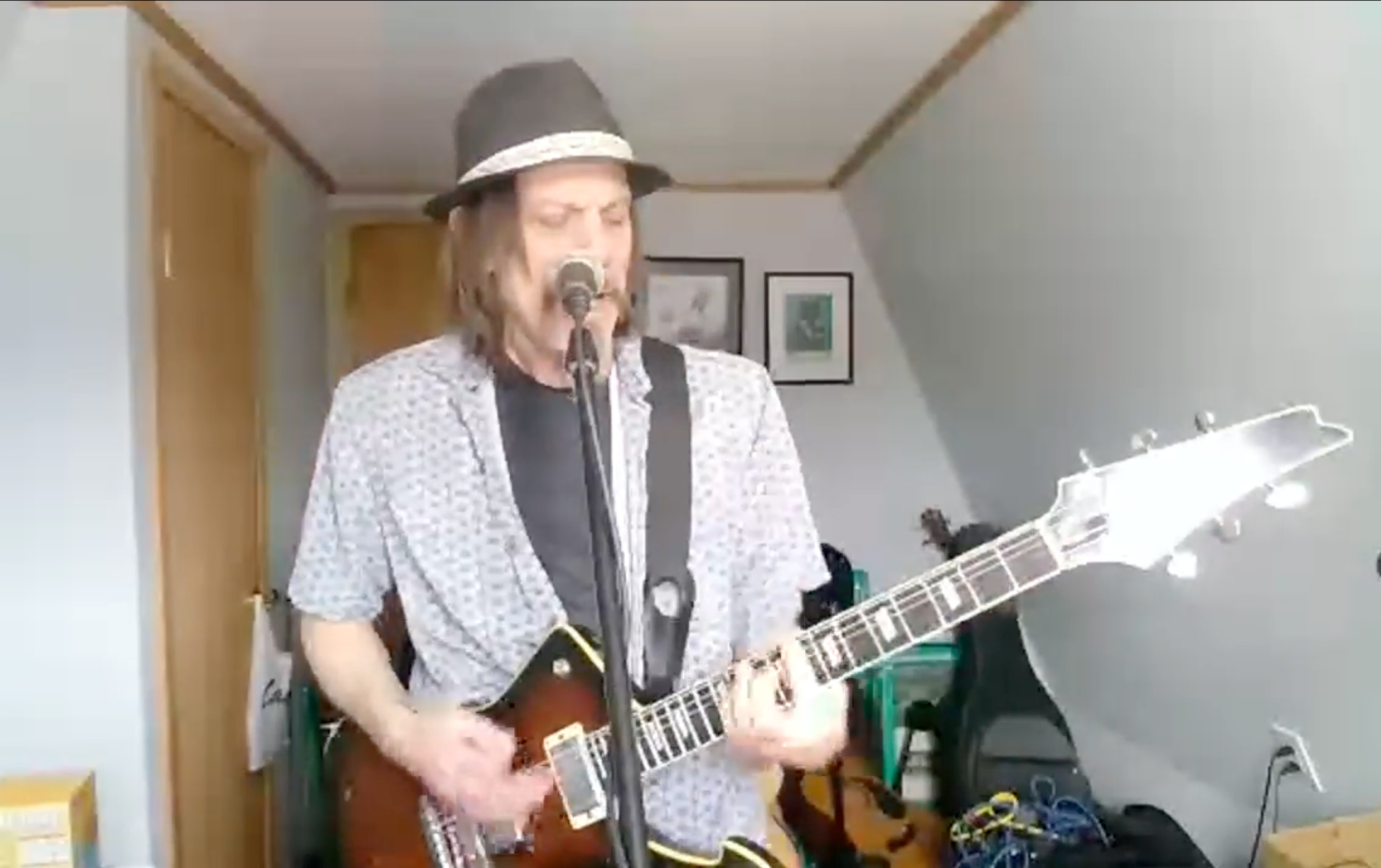 A man with a beard is playing an acoustic guitar in a room.