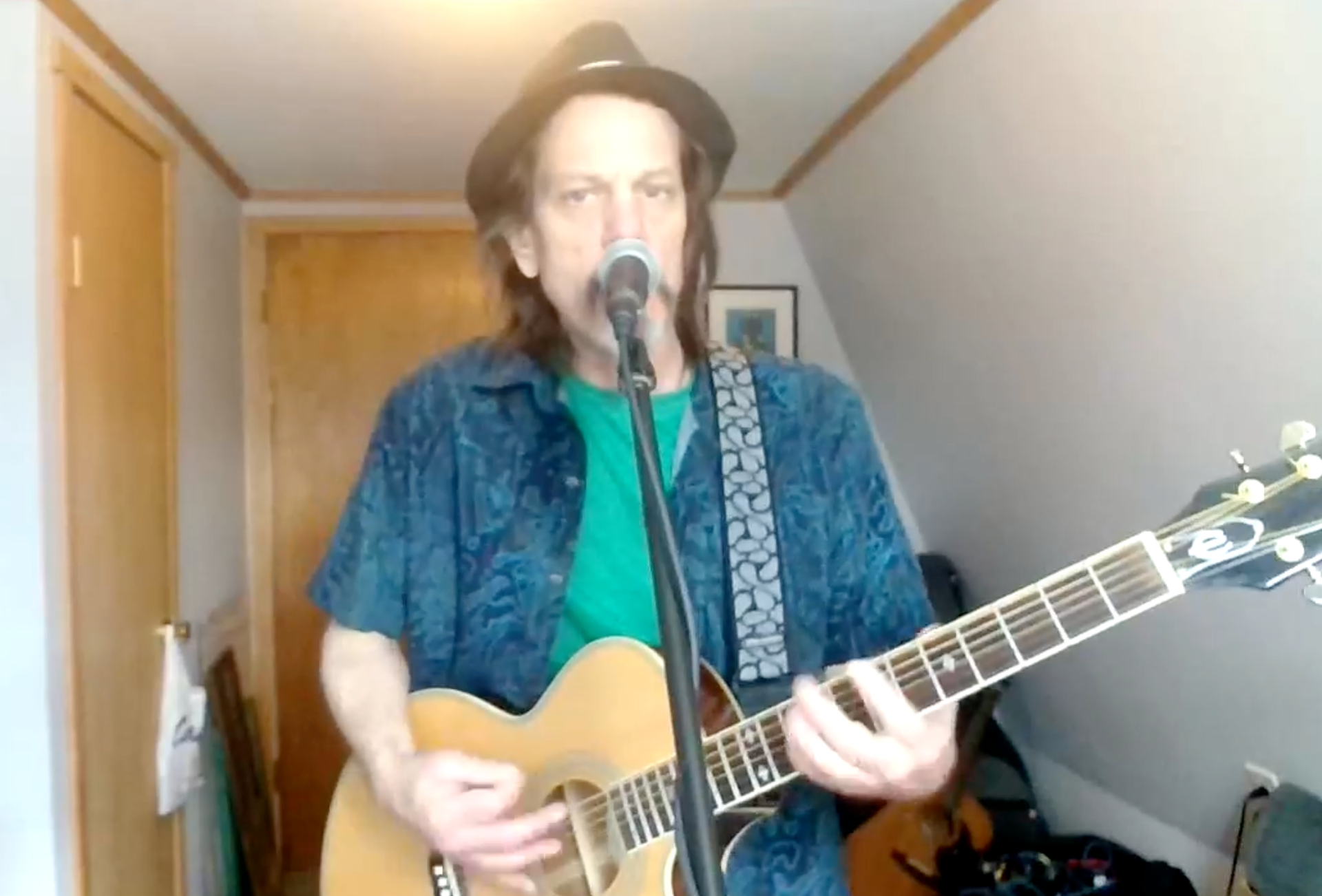 A man with a beard is playing an acoustic guitar in a room.