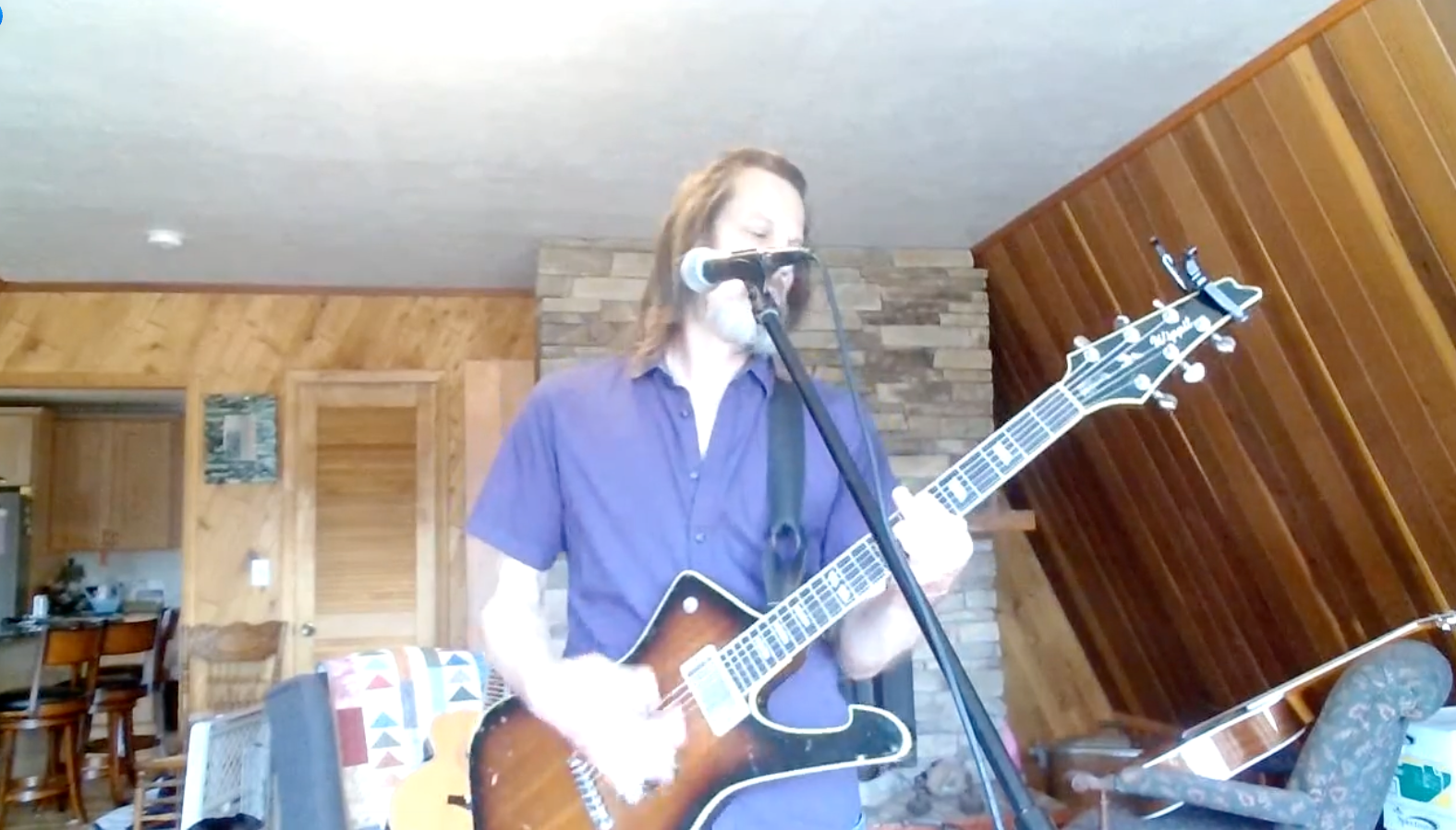 A man with a beard is playing an acoustic guitar in a room.