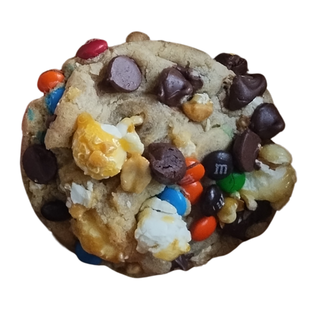 Close-up of a round cookie with various toppings, including chocolate chips, candies, and kettle corn.