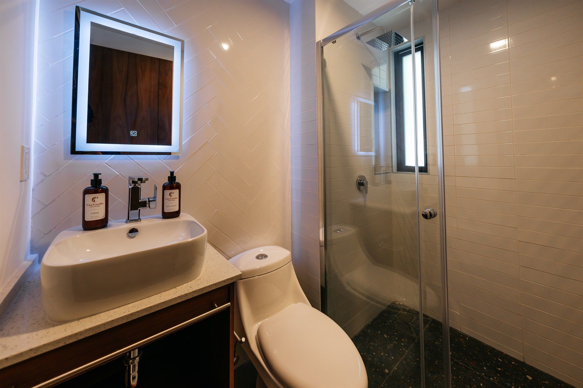 Un baño con inodoro, lavabo, espejo y ducha.
