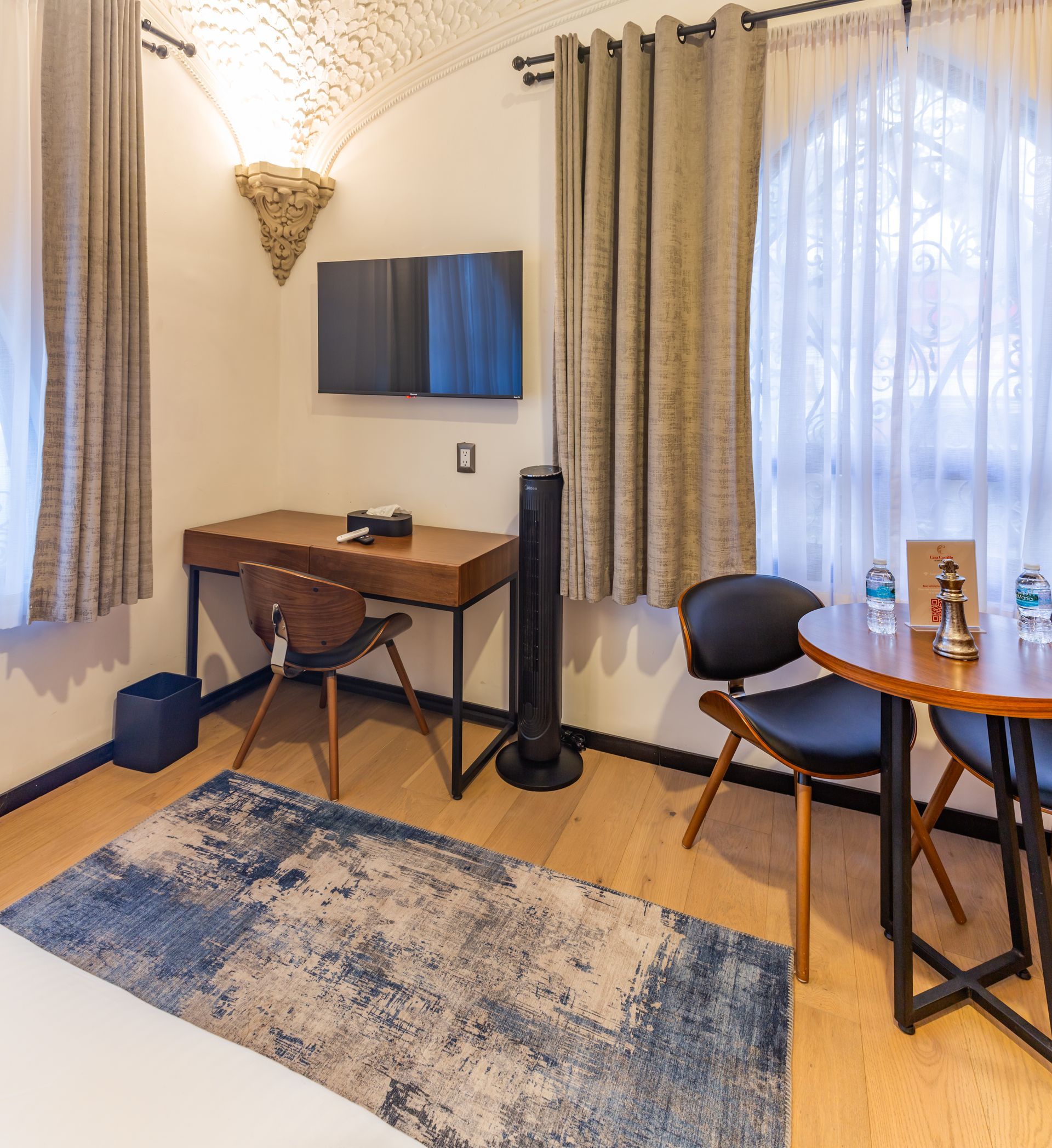 A hotel room with a table and chairs and a desk
