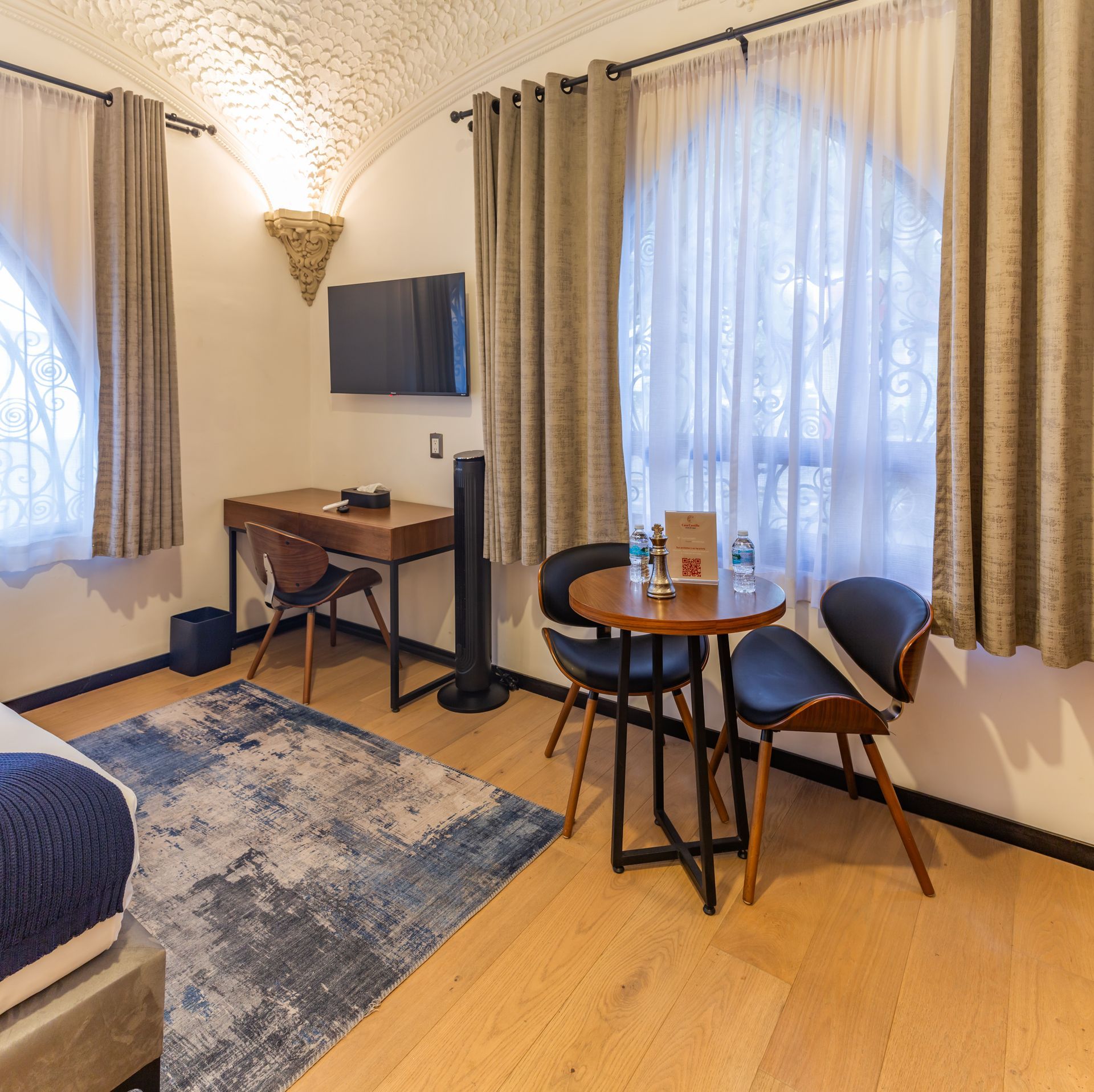 A hotel room with a table and chairs and a flat screen tv