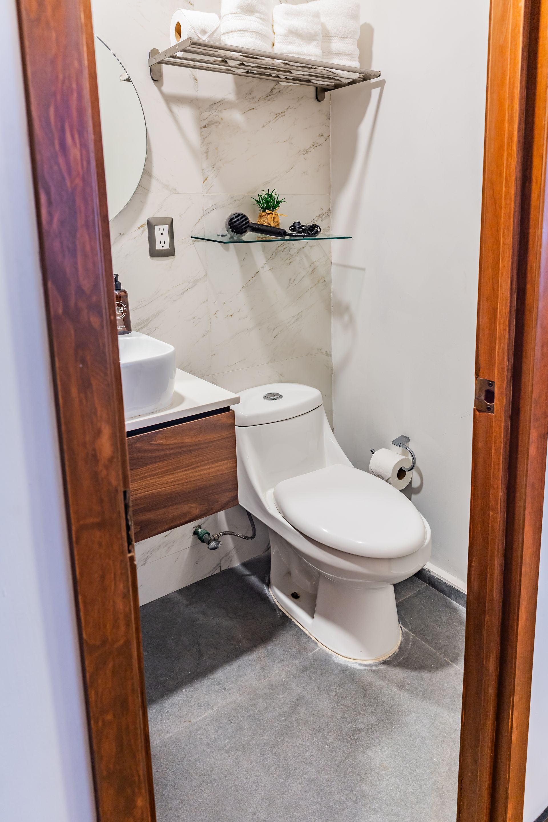 A bathroom with a toilet , sink and mirror.