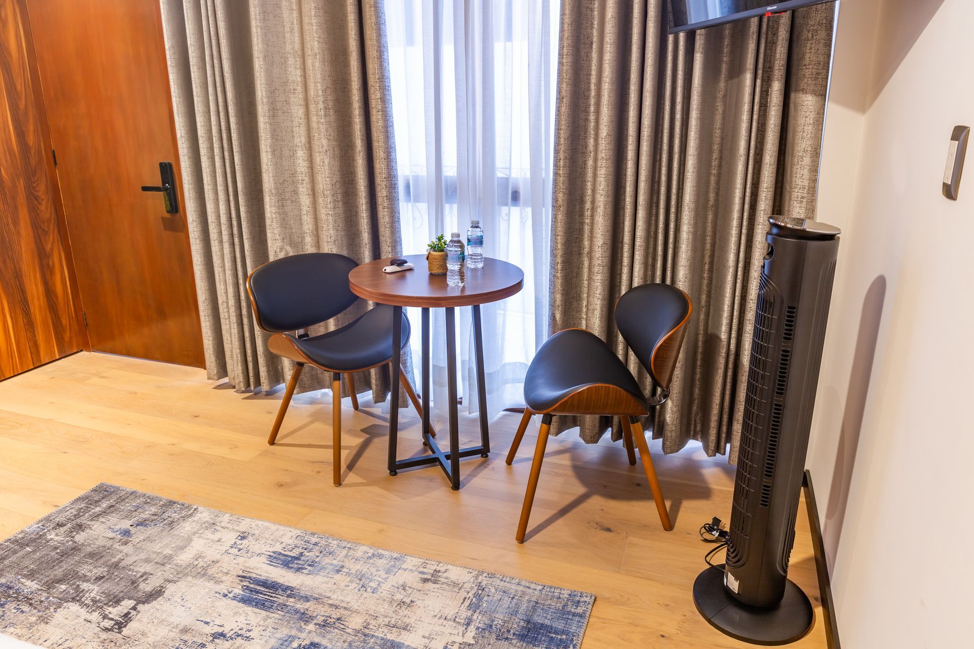 Una habitación de hotel con una mesa y sillas frente a una ventana.