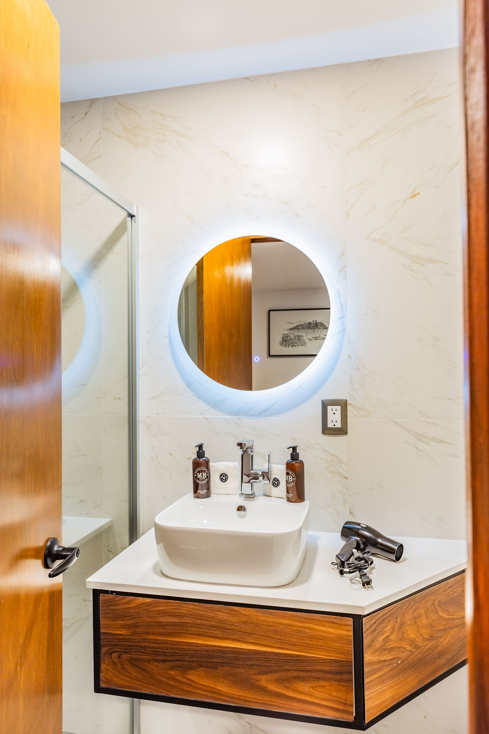 Un baño con lavabo, espejo y mueble de madera.