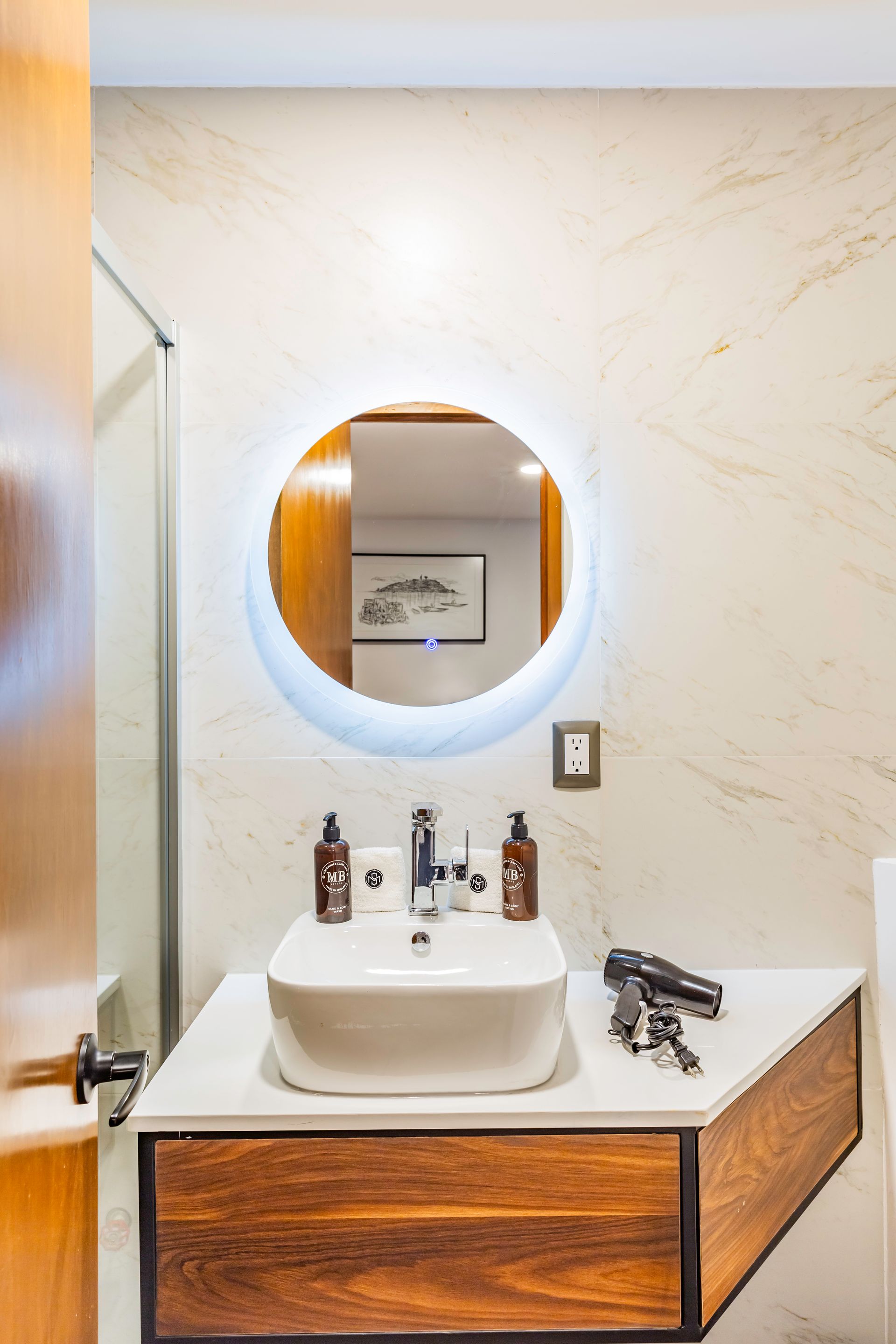 Un baño con lavabo, espejo y mueble de madera.