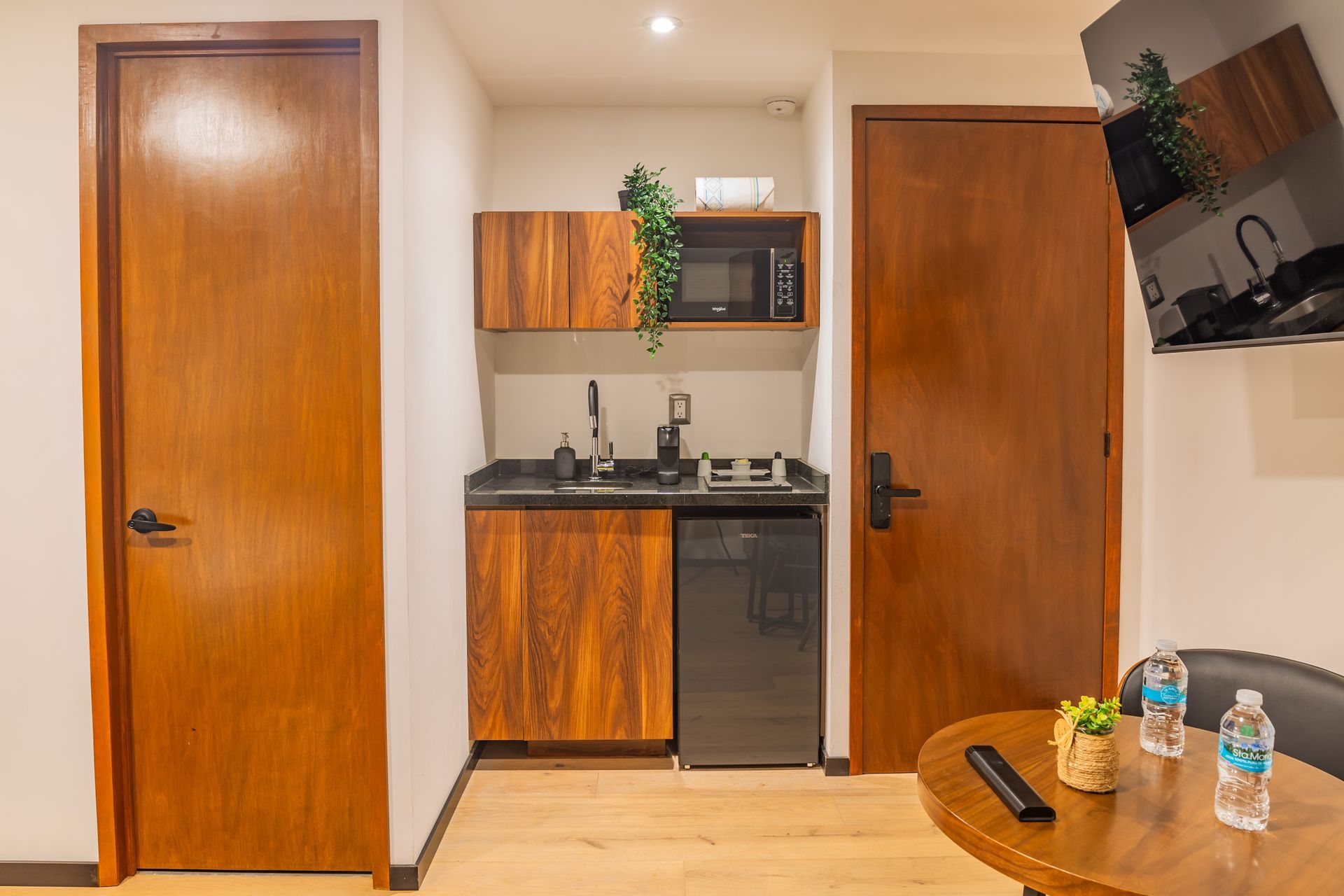 Una cocina con muebles de madera, un fregadero, un microondas y una mesa.