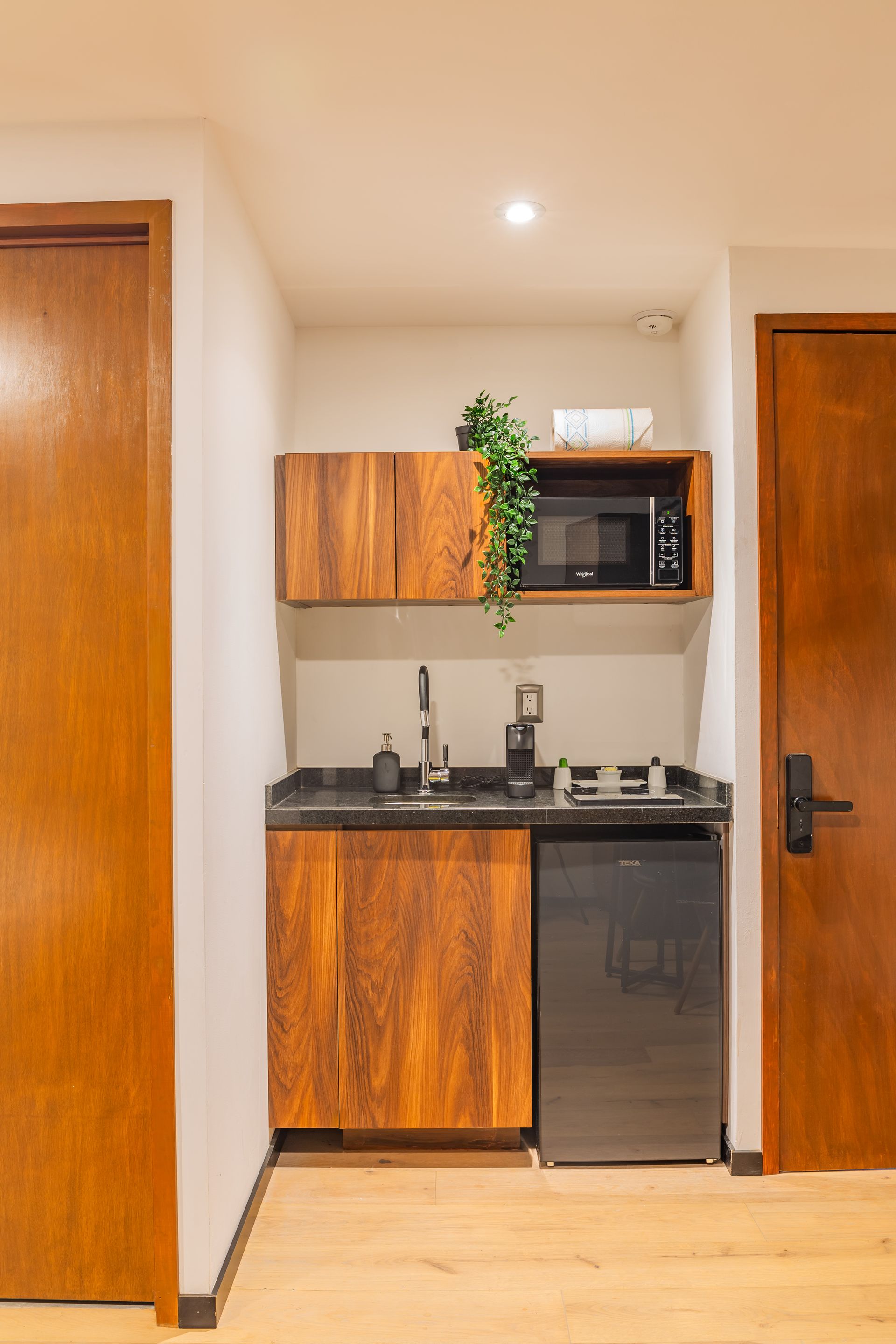 Una pequeña cocina con gabinetes de madera, un microondas y un refrigerador.