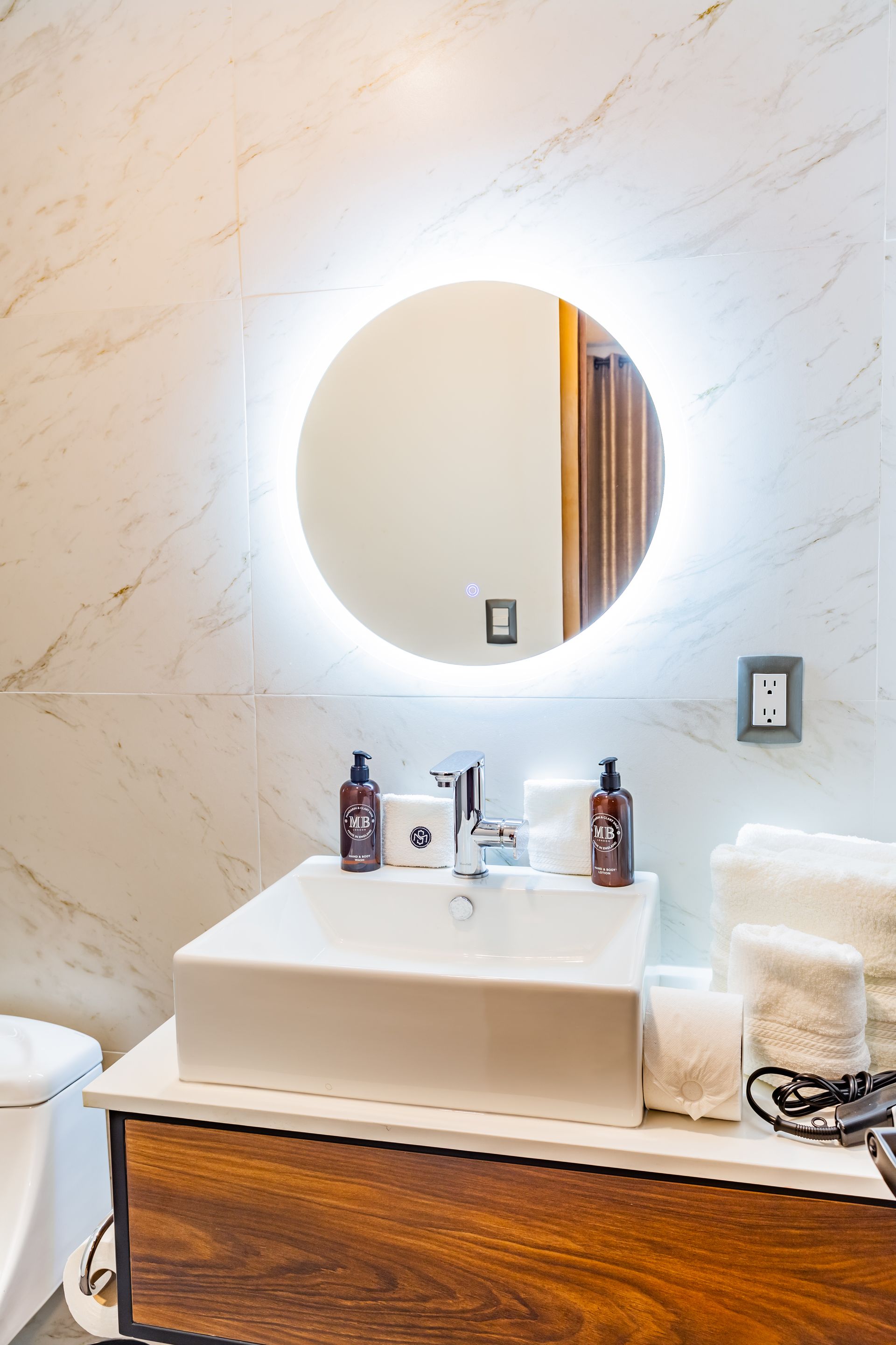 Un baño con lavabo, espejo e inodoro.