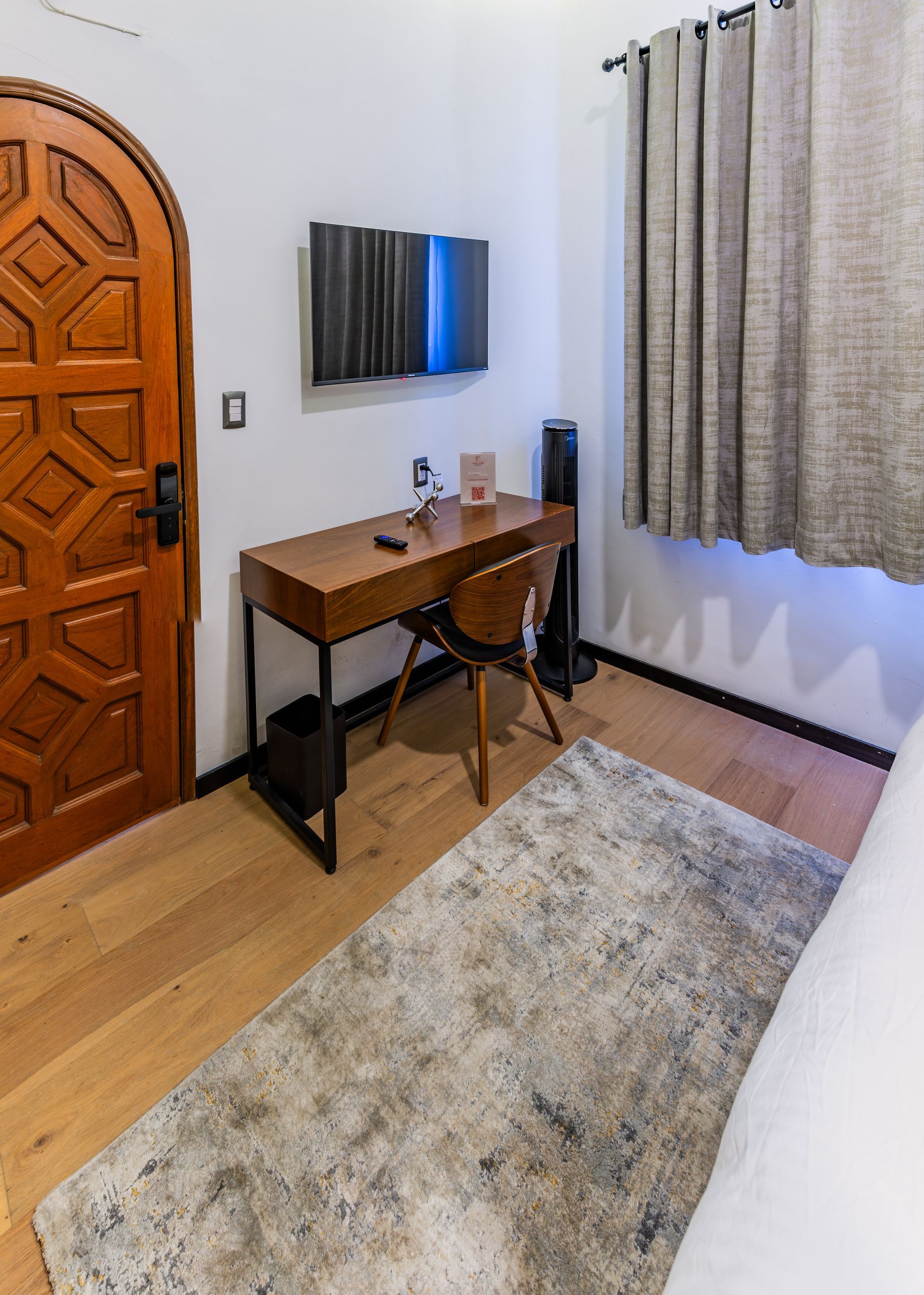 A bedroom with a desk and chair and a rug