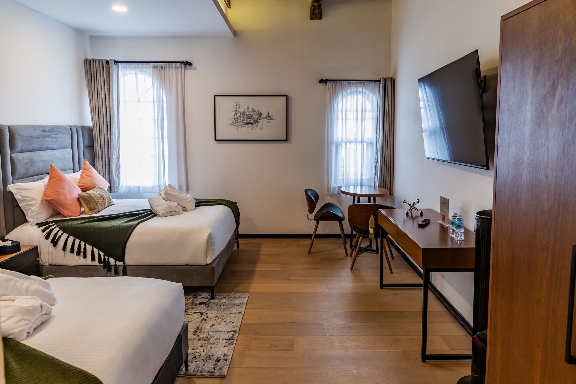 Una habitación de hotel con dos camas, un escritorio y un televisor de pantalla plana.