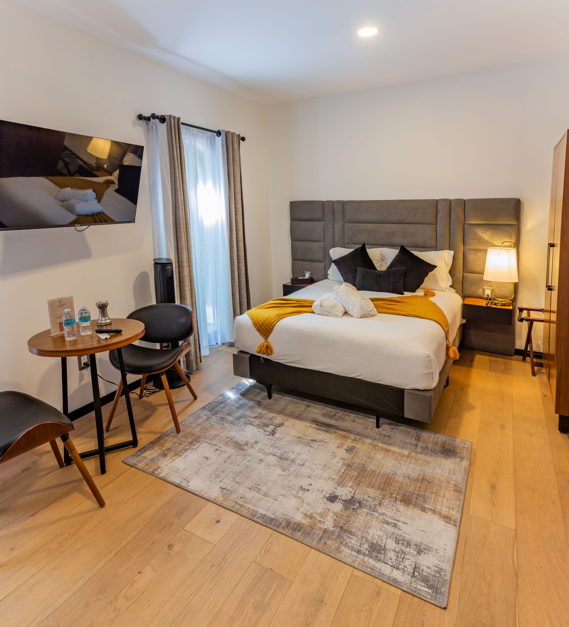 Una habitación de hotel con una cama tamaño king, mesa y sillas.