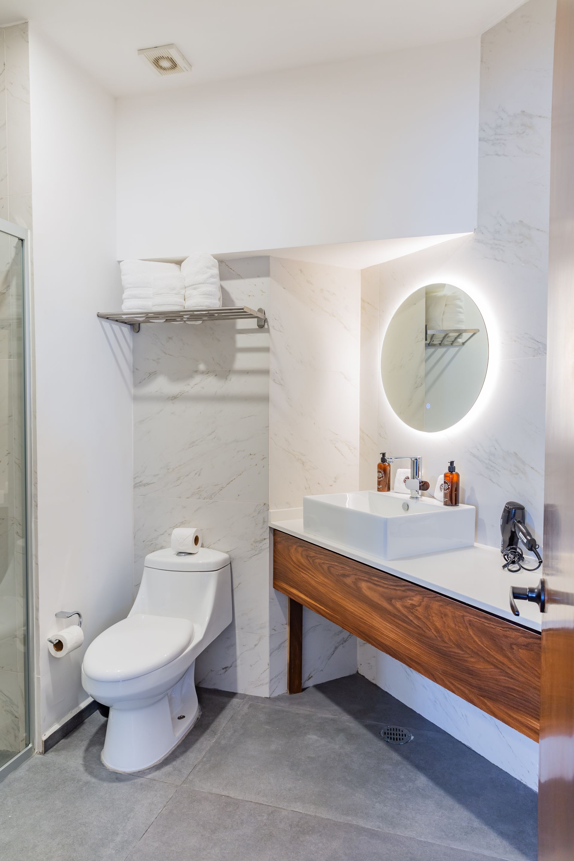 Un baño con inodoro, lavabo, espejo y ducha.