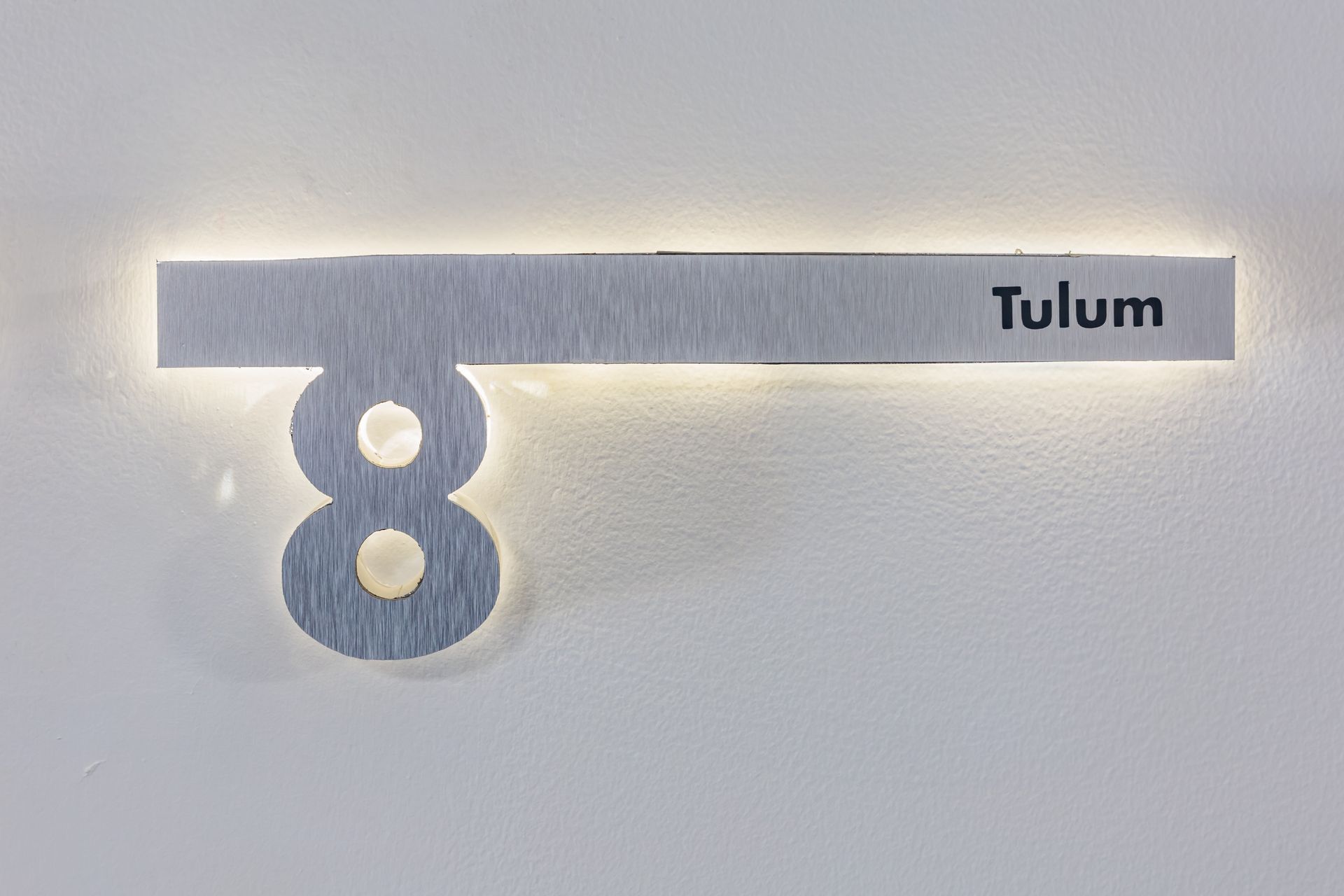 Un cartel que dice Tulum está en una pared blanca.