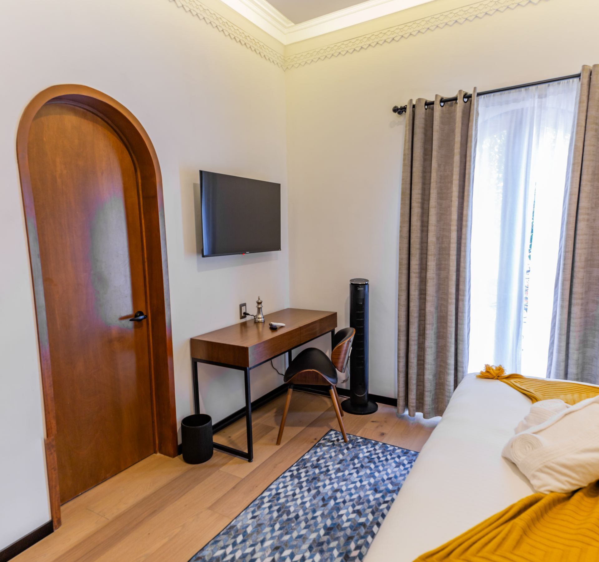 Un dormitorio con una cama, un escritorio y un televisor de pantalla plana.