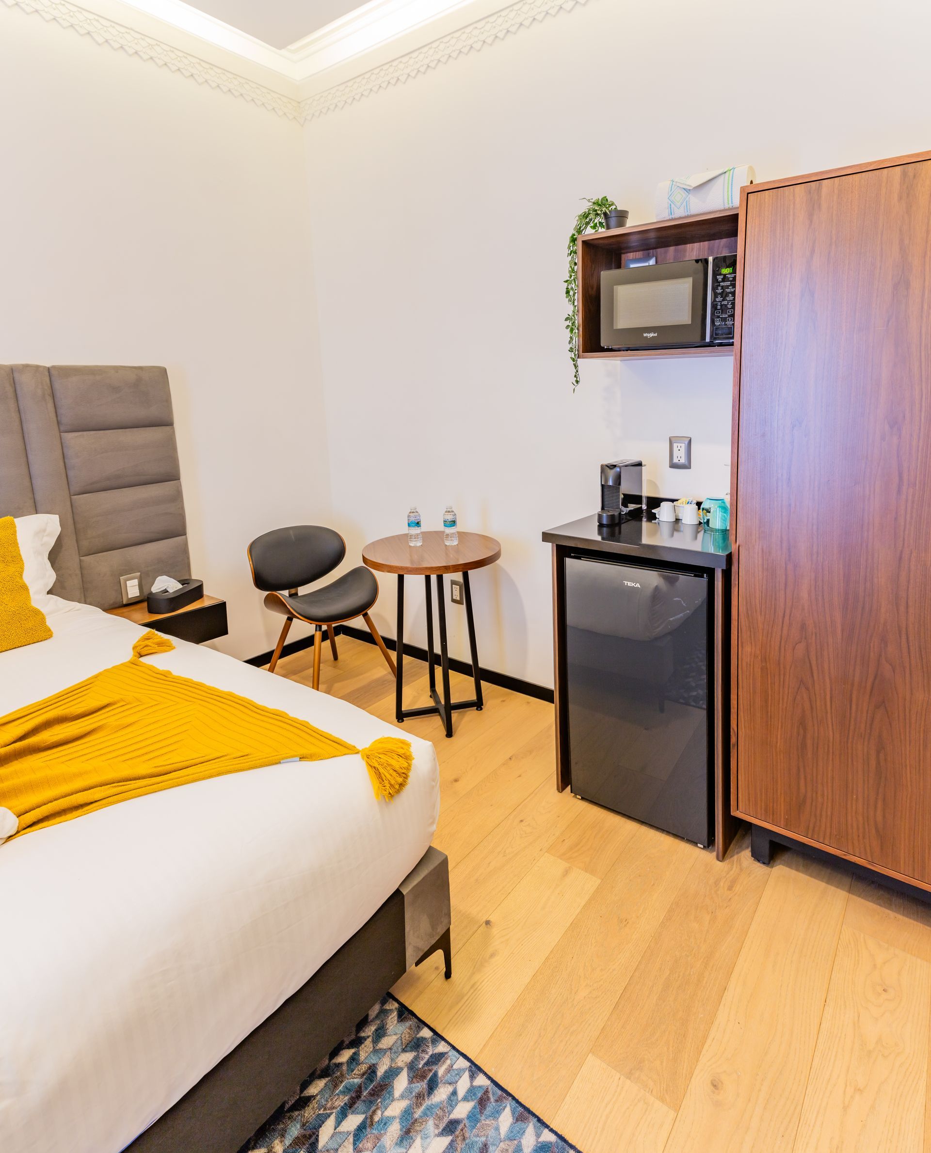 Una habitación de hotel con una cama, una silla, una mesa y un refrigerador.