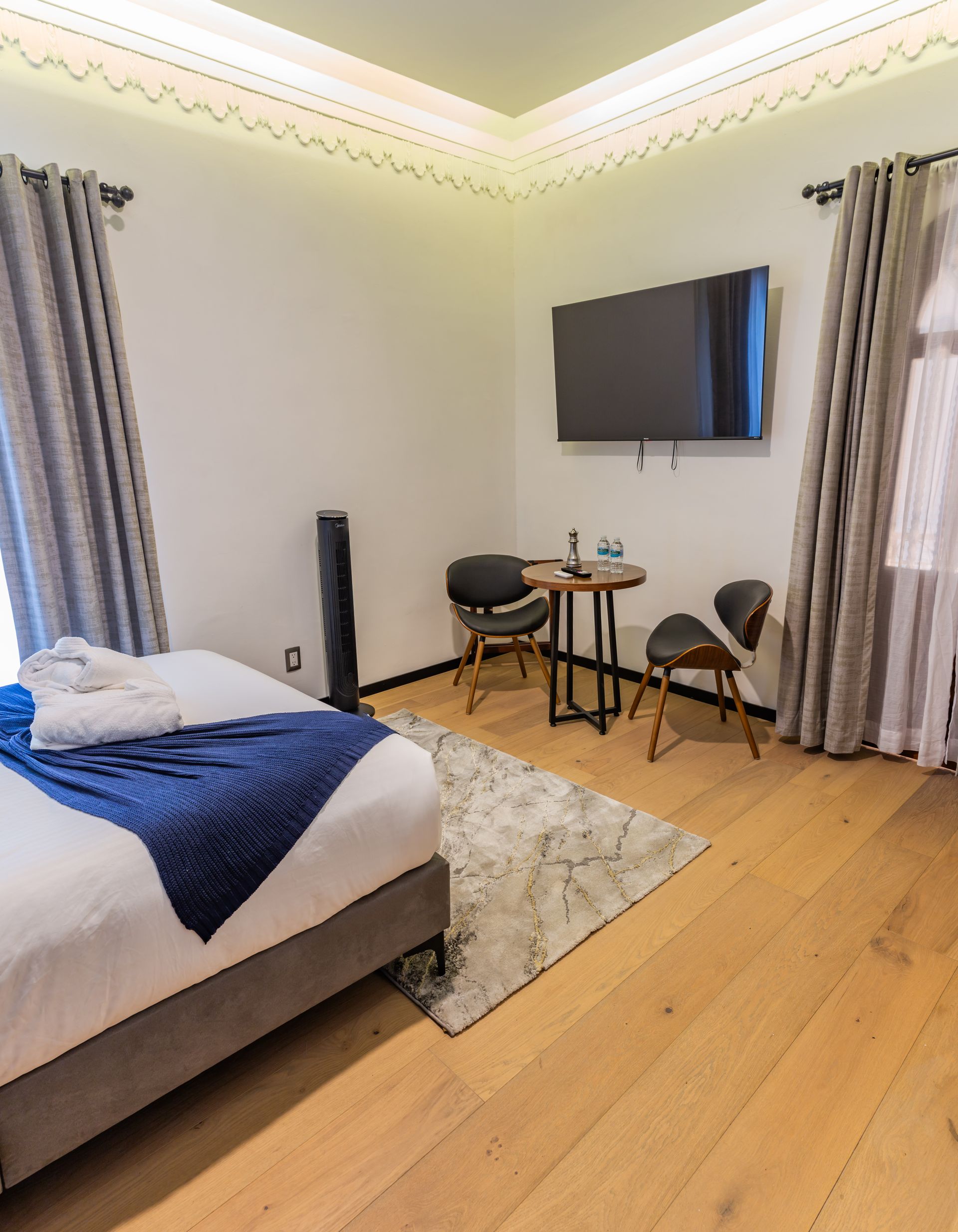 Una habitación de hotel con una cama, sillas, mesa y televisión.