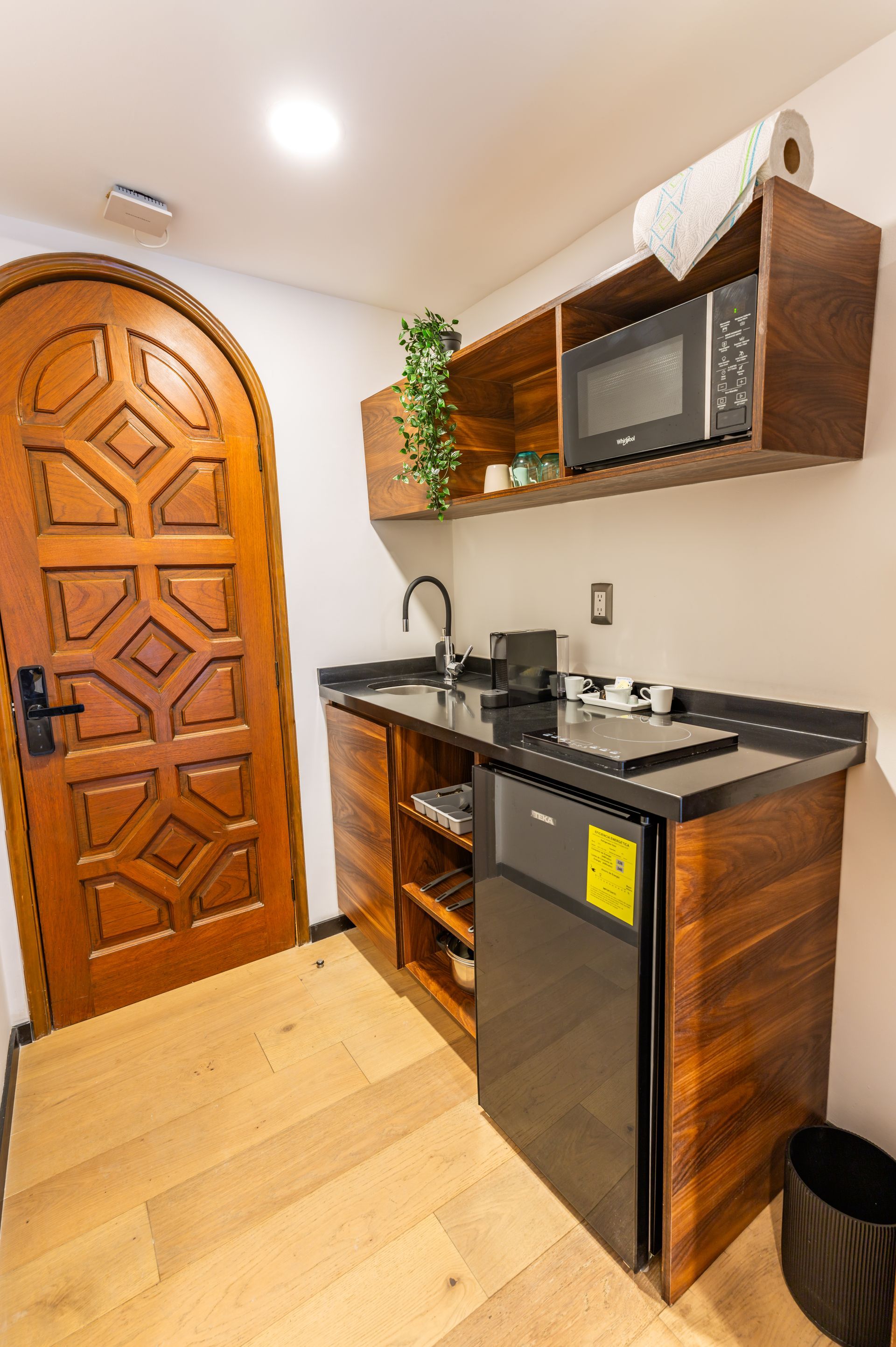 Una cocina con microondas, frigorífico, fregadero y puerta.